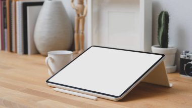 Modern çalışma alanındaki ofis malzemeleri ve kahve fincanı ile boş ekran tabletinin görüntüsünü kapat