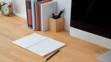 Ahşap masa arkasında defter, bilgisayar ve ofis malzemeleri ile modern çalışma alanı görünümünü kapat 