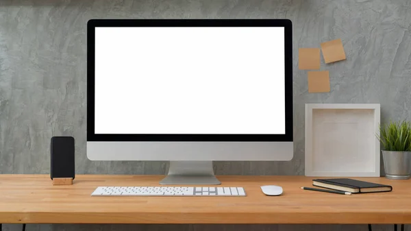 Close up άποψη του υπολογιστή γραφείου κενή οθόνη με κολλώδη σημείωση, πλαίσιο και προμήθειες γραφείου με πατάρι γκρι φόντο τοίχο — Φωτογραφία Αρχείου