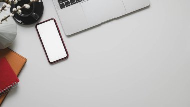 Bilgisayarlı, akıllı telefonlu ve ofis malzemelerinin bulunduğu ofis odasının üst görüntüsü beyaz masa zemininde fotokopi alanı olan 