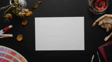 Overhead shot of workplace with sketch paper and painting tools on black table