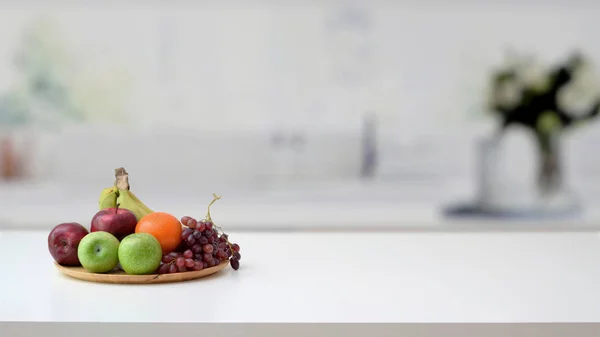 Close up άποψη του δίσκου φρούτων και αντίγραφο χώρο σε μαρμάρινο γραφείο με θολή κουζίνα room — Φωτογραφία Αρχείου