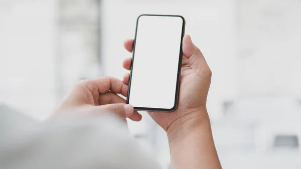 Tiro cortado de empresário tocando smartphone tela em branco com sala de escritório borrada — Fotografia de Stock