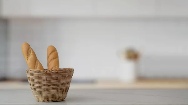 Nahaufnahme von französischem Baguette-Korb und Kopierraum auf Marmortisch mit verschwommener Küche — Stockfoto