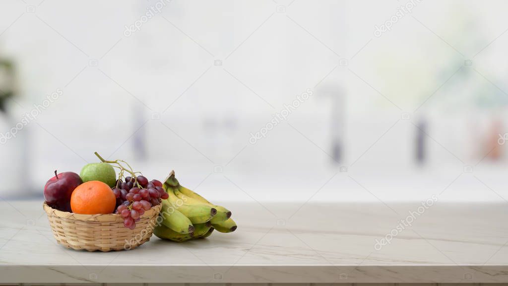 Cropped shot of fruit basket and copy space on marble desk with blurred kitchen room