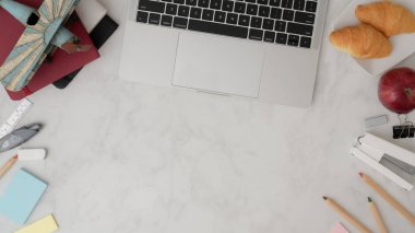Sanatçı çalışma alanının en üst görüntüsü kopya alanı, laptop, kırtasiye malzemesi, ofis malzemeleri, kahvaltı ve mermer masa üzerindeki renkli kalemler 