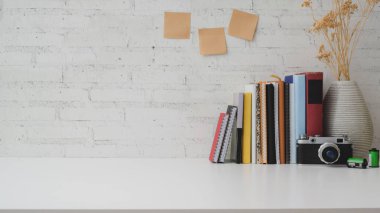 Fotokopi alanı, kitaplar, dekorasyonlar, yapışkan notlar ve beyaz masadaki tuğla duvar zeminli kamera ile kırpılmış çalışma alanı 