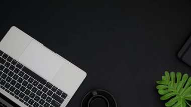 Siyah masada çalışma alanı, dizüstü bilgisayarı, klavyesi ve akıllı telefonu olan en üst görünüm 