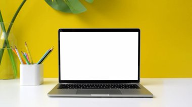 Çalışma alanının görüntüsünü boş ekran dizüstü bilgisayar, kalem ve vazo ile kapatın. 