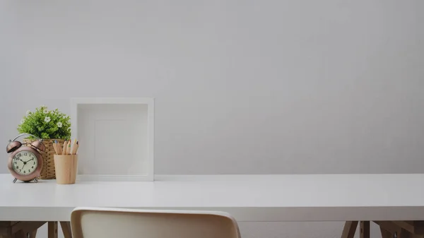 Cropped shot of workspace with copy space, decorations, frame and coloured pencils on white table with white wall — 스톡 사진