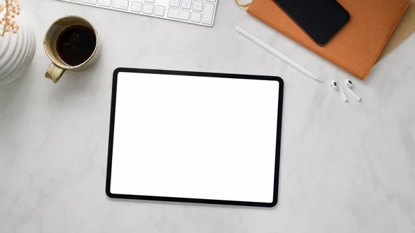 Top view of workspace with blank screen tablet, smartphone, coffee cup and office supplies on marble desk