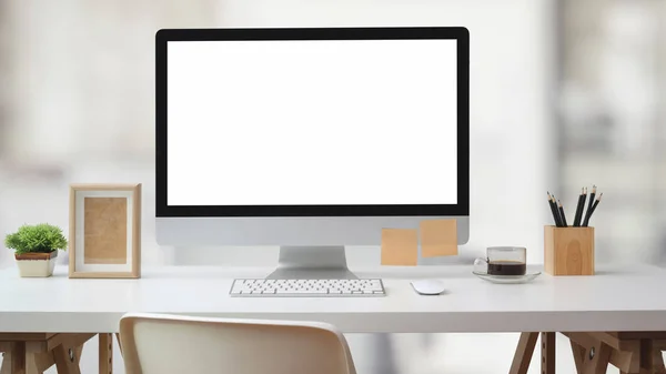 Zavřít pohled na pracovní prostor s prázdnou obrazovkou počítače, kancelářské potřeby a dekorace na bílém stole s rozmazané kancelářské místnosti — Stock fotografie