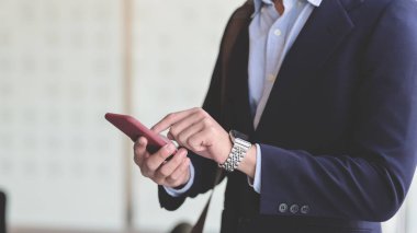 Ofiste dikilirken akıllı telefonlara dokunan işadamının yakın görüntüsü