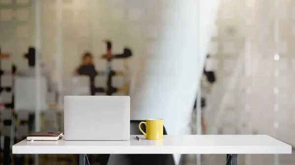 Close up άποψη του χώρου εργασίας με φορητό υπολογιστή, προμήθειες γραφείου, φλιτζάνι καφέ και αντίγραφο χώρο σε λευκό τραπέζι με θολή αίθουσα γραφείου — Φωτογραφία Αρχείου