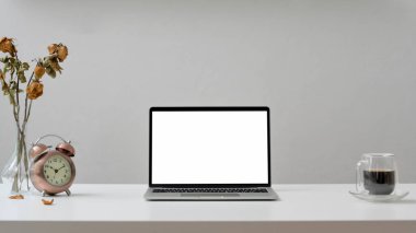 İşyeri manzarasını kapat. Laptop, kahve fincanı ve beyaz ahşap masa ve beyaz duvar arkaplanlı süslemeler. 