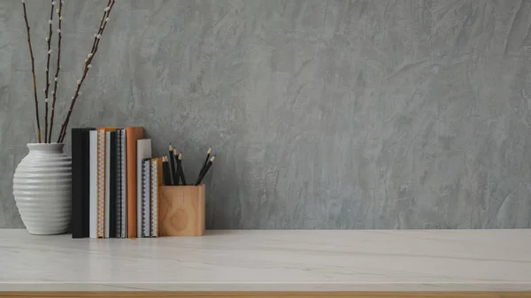 Κοντινό πλάνο χώρου εργασίας με βιβλία, γραφική ύλη και κεραμικό αγγείο σε μαρμάρινο γραφείο με φόντο γκρι πατάρι τοίχου — Φωτογραφία Αρχείου