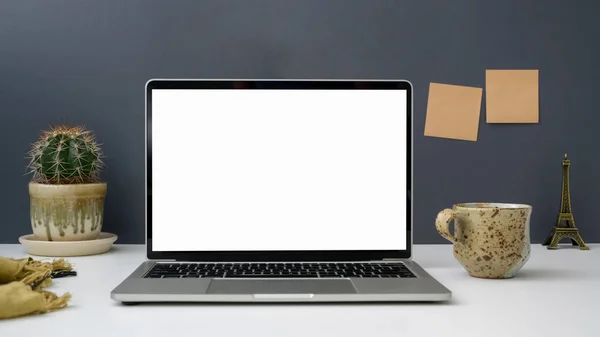 Close up view of workspace with open blank screen laptop, kubek, lepka nuta i dekoracje na białym stole z szarym tle ściany — Zdjęcie stockowe