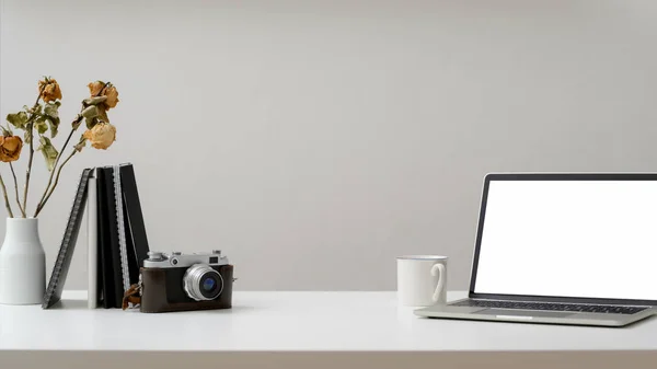 Captura recortada de espacio de trabajo con computadora portátil, cámara, café, suministros de oficina y jarrón asado seco en una mesa de madera blanca —  Fotos de Stock