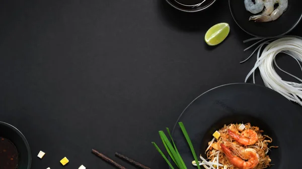 Nad hlavou záběr Pad Thai, míchat mouchu thajské nudle s krevetami, vejce a ingredience s kopírovacím prostorem v černé keramické desky na černém stole — Stock fotografie