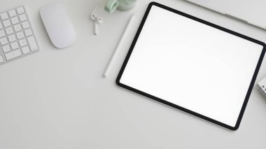 Beyaz masa arkasında dijital tablet, kopyalama alanı, bilgisayar, dizüstü bilgisayar ve ofis malzemelerinin bulunduğu çalışma alanının en üst görünümü