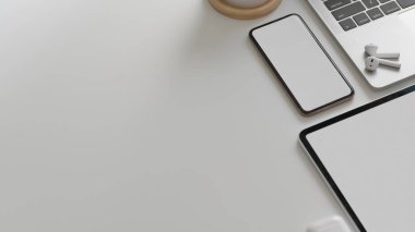 Akıllı telefon, tablet, dizüstü bilgisayar, kablosuz kulaklık ve beyaz masa arkaplanındaki kopyalama alanının üst görüntüsü