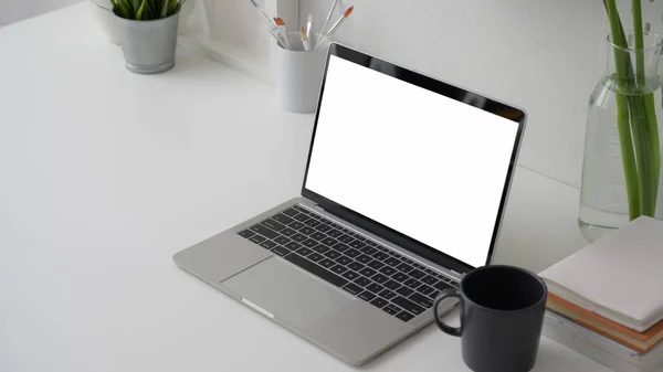 Tiro recortado do espaço de trabalho com laptop tela em branco, pincel de pintura e xícara de café no fundo da mesa branca — Fotografia de Stock