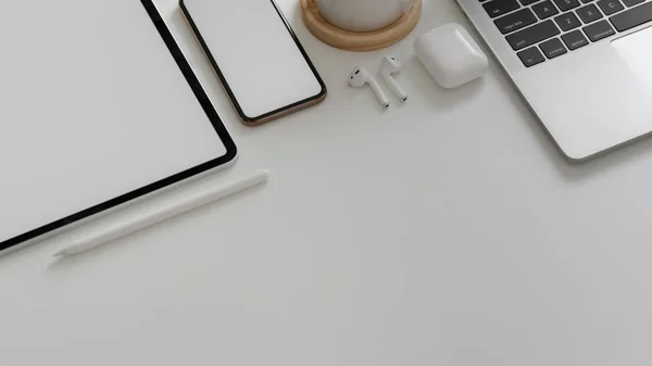 Toma aérea de teléfono inteligente, tableta, computadora portátil, auriculares inalámbricos, taza de café y espacio de copia sobre fondo de mesa blanco — Foto de Stock