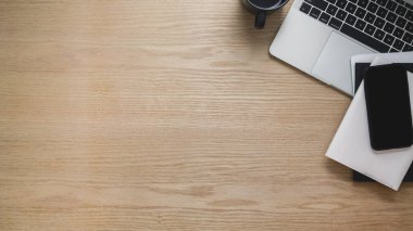 Akıllı telefon, laptop, fotokopi alanı ve ahşap masa arkasındaki diğer ofis malzemeleriyle çalışma alanının genel görüntüsü.