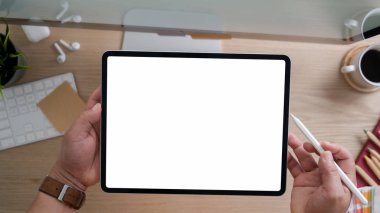 Modern kırsal ofis odasında bilgisayar ve ofis malzemeleriyle çalışırken tablet kullanan tasarımcının üst görünümü 