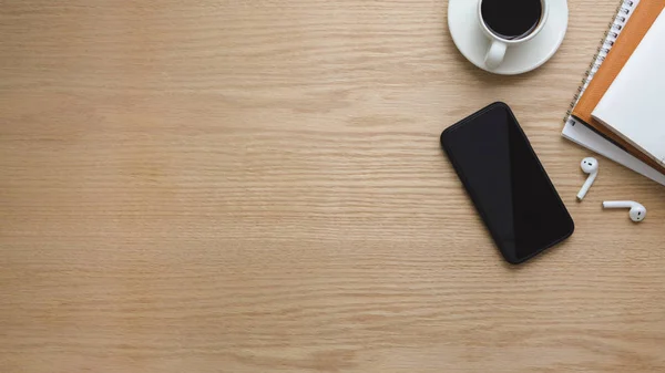 Top view of workspace with  smartphone, copy space, coffee cup and office supplies on wooden table background