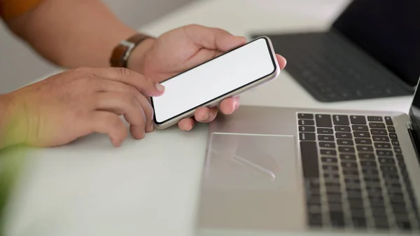 Vista lateral do freelancer masculino usando smartphone no espaço de trabalho com laptop e tablet no fundo da mesa branca — Fotografia de Stock