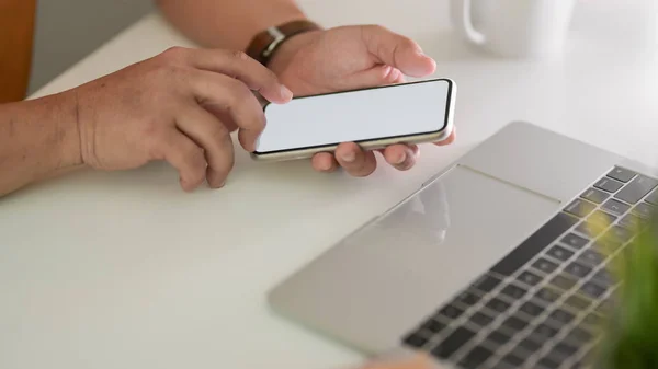 男自由撰稿人在工作空间用智能手机与笔记本电脑在白桌背景下发短信的剪影 — 图库照片