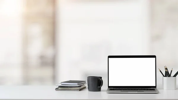 Vista de perto do espaço de trabalho com laptop, material de escritório e material de escritório e xícara de café na mesa branca com fundo embaçado — Fotografia de Stock