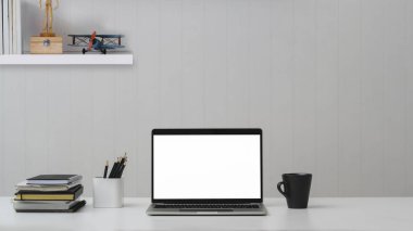 Boş ekran dizüstü bilgisayarı, ofis malzemeleri ve beyaz masa üzerindeki raflı kahve fincanını kapat. 