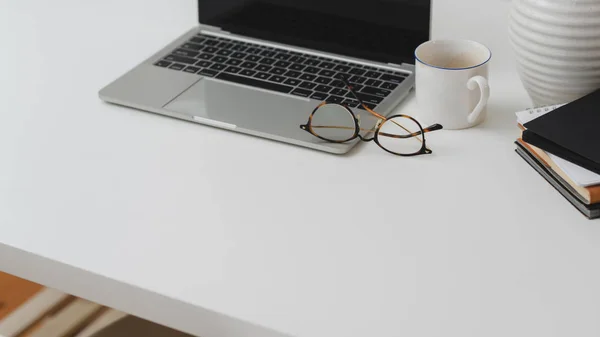 Captura recortada de espacio de trabajo con computadora portátil, suministros de oficina, taza de café y espacio de copia en el escritorio blanco —  Fotos de Stock