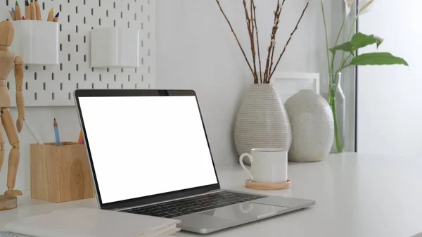 Cropped shot of modern designer workspace with mock up laptop, wooden figure and ceramic vase — 스톡 사진