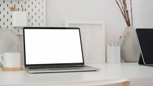 Boş ekran dizüstü bilgisayar, tablet, boya fırçası ve süslemelerle asgari düzeyde sanatçı işyeri görüntüsü — Stok fotoğraf