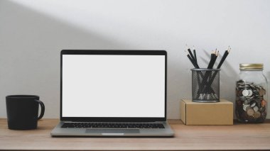Boş ekran laptop, kahve fincanı ve kırtasiye malzemesi ile basit çalışma alanı görünümünü kapat 
