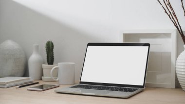 Boş ekran laptop, akıllı telefon, ofis malzemeleri ve dekorasyonla modern çalışma alanının kırpılmış görüntüleri. 