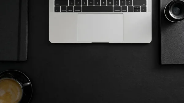 Снимок темного современного рабочего пространства с ноутбуком, кофейной чашкой и офисными принадлежностями — стоковое фото