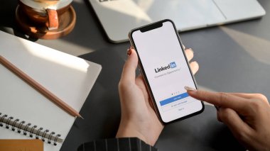 Chiang Mai, Tayland - 31 Ocak 2020: Linkedin ekranlı iPhone 'a dokunan kadın. Linkedin portföy oluşturulmasına ve yeni bir iş aranmasına yardımcı oluyor