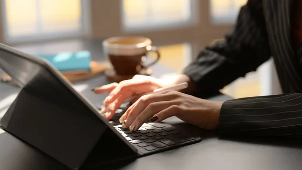 Vista lateral da digitação feminina no tablet digital na mesa preta no local de trabalho moderno — Fotografia de Stock