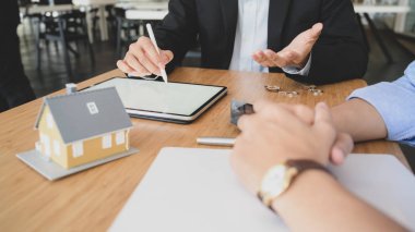 Cropped shot of House loan agent using  blank screen tablet while presenting to customer on wooden table background