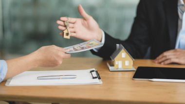 Close up view of real estate agent giving house key to his customer after signing  home loan agreement