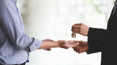 Close up view of real estate agent giving house key to his customer after finished signing home loan agreement