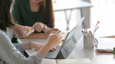 Close up view of designer team  brainstorming on their project while using digital tablet in simple co working space