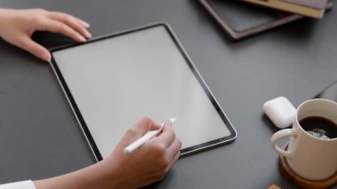 Siyah masa arkasına tablet çizen bir kadının kırpılmış görüntüsü.