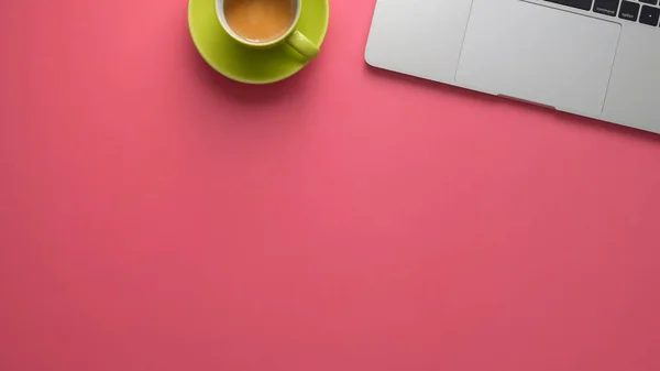 Top view of stylish workspace with laptop and copy space on pink table background