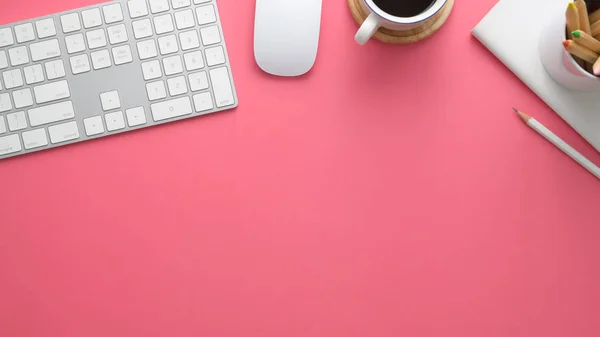 Overhead shot of stylish workspace with computer, stationery, computer, stationery, coffee cup and copy space on pink table background