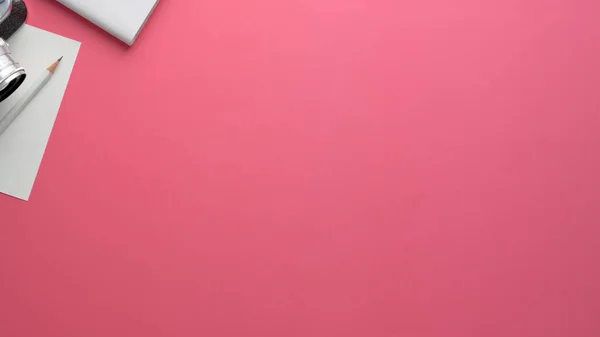 Fotografia aerea dello spazio di lavoro del fotografo con fotocamera, cancelleria e spazio copia su sfondo tavolo rosa — Foto Stock